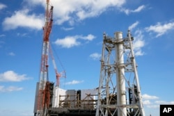 Reaktor Unit 1 yang rusak (bagian belakang), dan cerobong asap yang digunakan bersama oleh reaktor Unit 1 dan 2 terlihat di pembangkit listrik tenaga nuklir Fukushima Daiichi, yang dioperasikan oleh TEPCO, di Okuma, timur laut Jepang, Senin, 20 Februari 2025. (Eugene Hoshiko/AP)