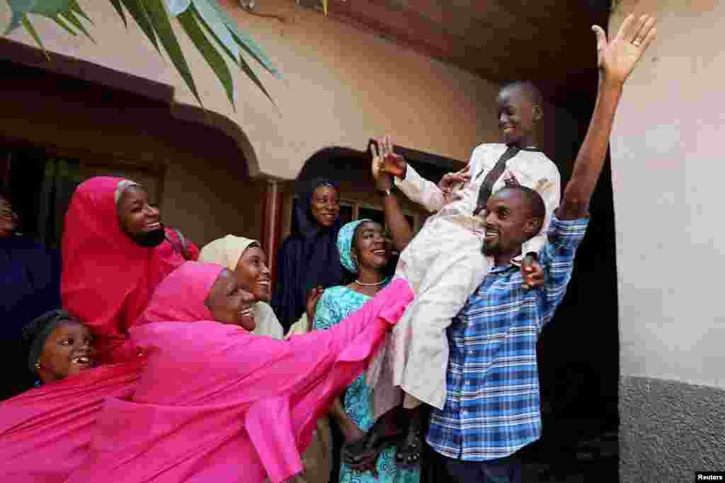 Muhammed Bello, a rescued student, is carried by his father as his relatives celebrate after he retuned home in Kankara, Nigeria, Dec. 19, 2020.