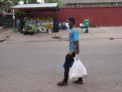 Oliver Tetteh carries packages of staple foods to distribute to households in Ghana's capital Accra, a city which has been in a partial lockdown since March 30, with many people out of work. (Stacey Knott/VOA)