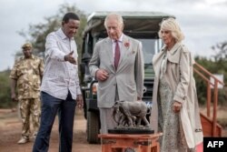 El rey Carlos III de Gran Bretaña (centro) y la reina Camilla de Gran Bretaña escuchan al secretario del gabinete de Turismo y Vida Silvestre de Kenia, Albert Mutua en el sitio de quema de marfil del Parque Nacional de Nairobi, el 1 de noviembre de 2023. (Foto de Luis Tato/AFP)