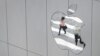 FILE - A woman is reflected in a Apple store logo in San Francisco, California, Aug. 21, 2017. 