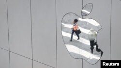 FILE - A woman is reflected in a Apple store logo in San Francisco, California, Aug. 21, 2017. 