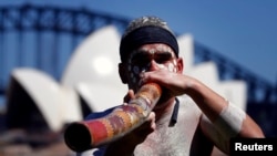 Seorang pria Aborigin memainkan alat musik tradisional "didgeridoo" di depan Gedung Opera Sydney, Australia, 27 November 2013. (Foto: dok).