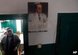Uros Trainovic walks inside his house decorated with a picture of former Yugoslav communist leader Josip Broz Tito, in the village of Blagojev Kamen, Serbia, Jan. 23, 2020.