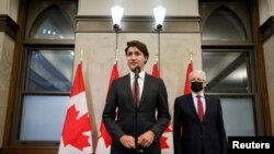 Canada's Prime Minister Justin Trudeau, accompanied by Foreign Minister Marc Garneau, holds a press conference as he tells reporters that two Canadian citizens who were detained by Beijing have left Chinese airspace, in Ottawa, Sept. 24, 2021.