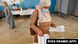 Une femme ramasse un bulletin de vote dans un bureau de vote à Bouchaoui, dans la banlieue ouest d'Alger, la capitale algérienne, le 12 juin 2021, lors des élections législatives de 2021.