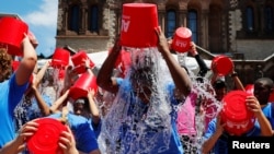 FILE - People pour buckets of ice water over her heads as part of the "ALS Ice Bucket Challenge," a viral activity started by Pat Quinn and Pete Frates to raise money for research into the ALS disease, in Boston, Massachusetts, July 15, 2019.