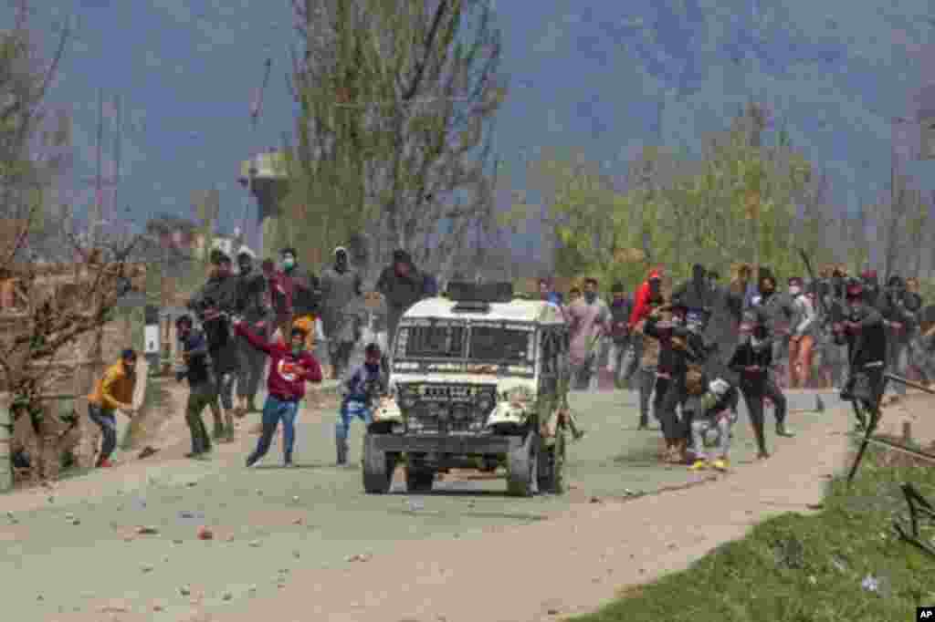 Kashmiri villagers throw stones and bricks at a police vehicle during a protest near the site of a gunbattle in Pulwama, south of Srinagar, Indian-controlled Kashmir.