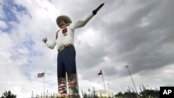 FILE - Bluebonnets, the state flower of Texas, surround Big Tex as storm clouds move in above, Sept. 27, 2013, in Dallas. 