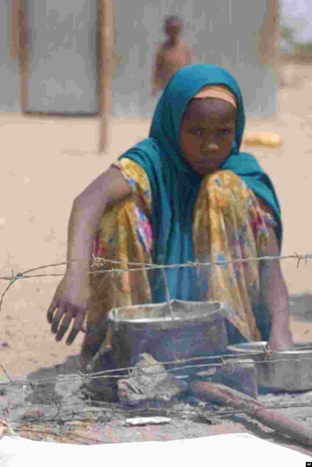 A girl warms some food on a makeshift fire shortly after arrival at the Dollo Ado refugee reception center. VOA - P. Heinlein