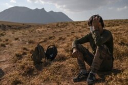 FILE - An Afghan migrant rests while waiting for transport by smugglers after crossing the Iran-Turkish border on August 15, 2021 in Tatvan, on the western shores of Lake Van, eastern Turkey.