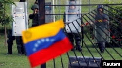 FILE - A member of the riot security forces points a gun at an opposition supporter holding a Venezuelan national flag during clashes at a rally against Venezuelan President Nicolas Maduro's government in Caracas, June 22, 2017. 