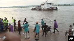 Quelques personnes contemplent, de la plage, un bateau qui passe sur le fleuve Congo, qui sépare Brazzaville et Kinshasa, à Kinshasa, RDC, 29 avril 2014.