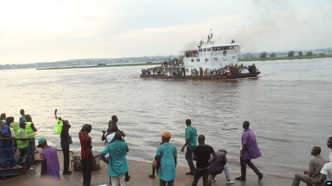 FILE - People that have been deported from Congo's capital Brazzaville, seen in background, arrive by river boat in Kinshasa, Democratic Republic of Congo, April 29, 2014.