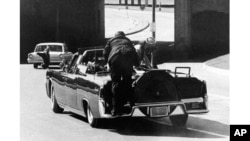 FILE - First lady Jacqueline Kennedy leans over President John F. Kennedy after he was shot, as Secret Service Agent Clint Hill pushes the first lady back to her seat, in Dallas, Texas, Nov. 22, 1963.