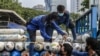 Pekerja menurunkan tangki oksigen di stasiun oksigen darurat di dekat Monas, Jakarta, 5 Juli 2021. (Foto : Mariana/AFP)
