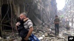 Picha inamuonyesha mwanamme akiwa amembeba mtoto baada ya shambulizi la anga huko Aleppo, Syria, Alhamisi April 28.