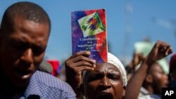 A protester holds up a copy of the Haitian Constitution during a protest to demand the resignation of Haiti's president Jovenel Moise in Port-au-Prince, Haiti, Feb. 10, 2021.