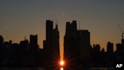 The sun rises through the middle of buildings long 42nd street in New York&#39;s Manhattan borough during a phenomenon known as Manhattanhenge as viewed from Weehawken, New Jersey.
