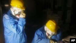 In this photo released by Nuclear and Industrial Safety Agency, Tokyo Electric Power Co. workers collect data in the control room for Unit 1 and Unit 2 at the tsunami-crippled Fukushima Dai-ichi nuclear power plant, March 23, 2011.