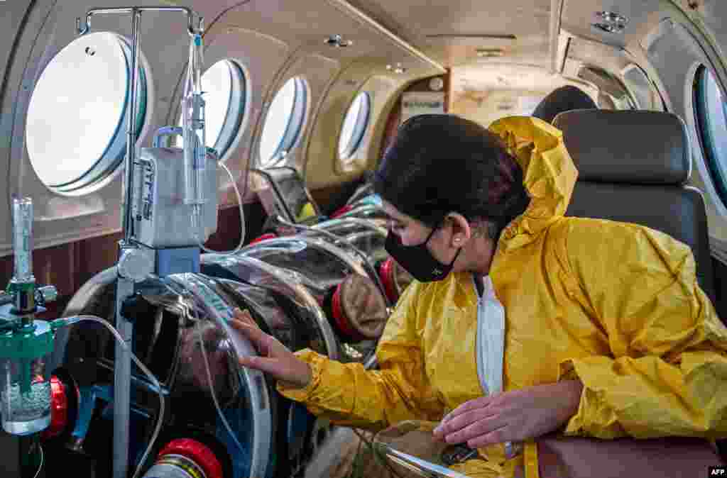 Andrea Lara (R) looks at her father Juan Carlos Lara, 59, a patient with COVID-19, as he is transferred inside a security capsule on an air ambulance from Iquitos to the Intensive Care Unit of the Rebagliati Hospital, in Lima, Peru.
