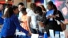 FILE - Carolina Wilson, with the United States Postal Service, left, talks with prospective job applicants at a job fair, Aug. 29, 2024, in Sunrise, Fla.