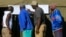 People look at results placed outside a polling station in Harare, Zimbabwe, July 31, 2018. 
