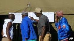 People look at results placed outside a polling station in Harare, Zimbabwe, July 31, 2018. 