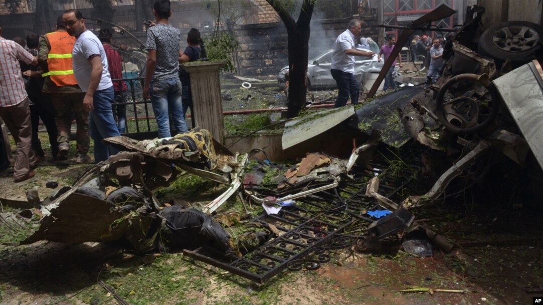 Warga dan petugas pemadam kebakaran berkumpul di lokasi jatuhnya roket yang menimpa rumah sakit Dubeet hospital di pusat daerah Muhafaza di Aleppo, Suriah (3/5).