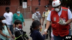 Un voluntario de la Cruz Roja entrega alimentos a los niños migrantes hondureños que regresan a Honduras en El Florido, Chiquimula, Guatemala el 19 de enero de 2021, en la frontera con Honduras.