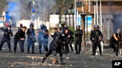 Seorang wanita Mesir berlari mencari tempat berlindung saat polisi anti huru-hara melemparkan batu di dekat gedung keamanan pemerintah setempat di Port Said (Foto: dok). Bentrokan polisi-pengunjuk rasa terus berlangsung, sementara pengadilan Mesir mempertahankan hukuman mati atas 21 terdakwa kasus kerusuhan sepakbola di wilayah ini.