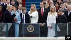 Donald Trump es juramentado ante su familia, mientras su esposa, Melania, sostiene las dos biblias que usó para la ocasión.