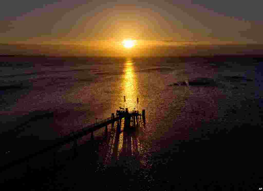 طلوع خورشید در ورای یک اسکله در دریای بالتیک در هافکروگ، شمال آلمان
