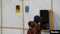 FILE - A woman and a girl are seen outside makeshift accommodations at camp for internally displaced people in Maiduguri, Nigeria, March 8, 2016.