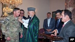 A handout photo shows Afghan President Hamid Karzai awarding a medal to outgoing International Security Assistance Force (ISAF) commander General David Petraeus at the Presidential Palace in Kabul, July 18, 2011