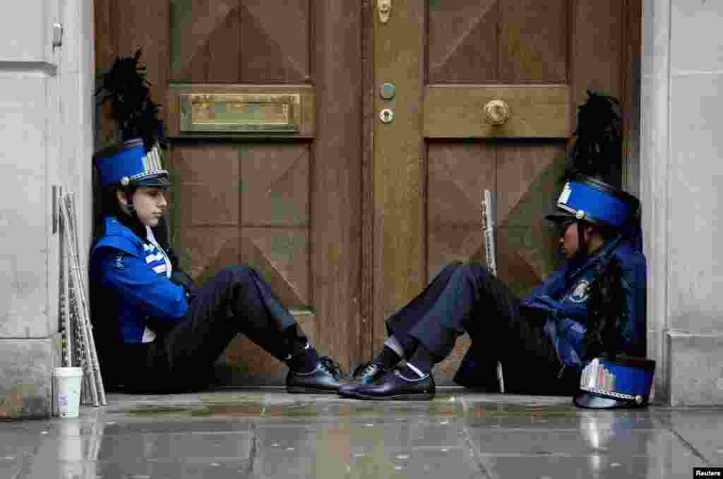Members of a marching band shelter from the rain before performing at the 28th annual New Year&#39;s Day parade in London.