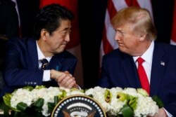 FILE - Japanese Prime Minister Shinzo Abe, left, shakes hands with President Donald Trump before signing a trade agreement on the sidelines of the United Nations General Assembly, in New York City, Sept. 25, 2019.