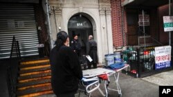 殡仪馆馆长汤姆·奇斯曼(中)和一位同事到纽约市布鲁克林区的一户人家接走一具遗体。(2020年4月3日)