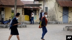 Women wearing face masks walk by the Yaba Mainland hospital, where an Italian citizen - the country's first case of the COVID-19 virus - is being treated, in Lagos, Nigeria Friday, Feb. 28, 2020.