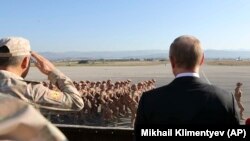 Tổng thống Nga Vladimir Putin (phải) nhìn binh sĩ diễu hành khi ông và Tổng thống Syria Bashar al-Assad thăm căn cứ không quân Hemeimeem ở syria, ngày 12 tháng 12, 2017.