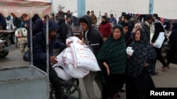 Palestinian men use a wheelchair to transport bags of flour distributed by the United Nations Relief and Works Agency (UNRWA), amid the ongoing conflict between Israel and Hamas, in Rafah in the southern Gaza Strip Jan. 29, 2024.