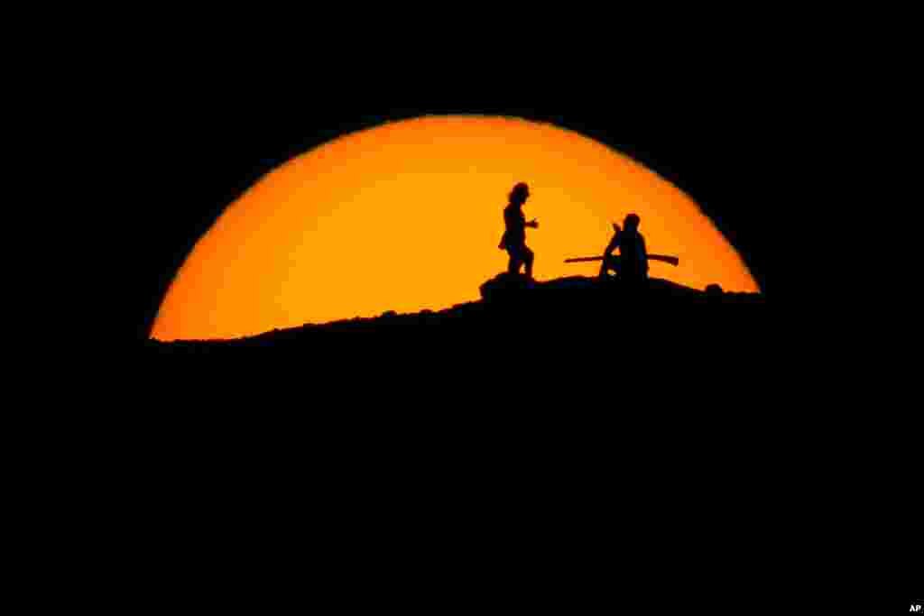 Hikers watch the sunset from a peak at Papago Park, Feb. 20, 2021, in Phoenix, Arizona.