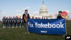 Para peserta kampanye dari AVAAZ mengangkat poster di depan 100 gambar potongan karton dari CEO Facebook, Mark Zuckerberg, di luar gedung Capitol AS, di Washington D.C., 10 April 2018 sebelum Mark Zuckerberg bersaksi. (Foto: Kevi Wolf/AP Images untuk AVAAZ).