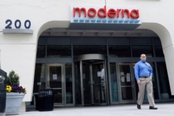 FILE - A man stands outside an entrance to a Moderna, Inc., building in Cambridge, Mass., May 18, 2020.
