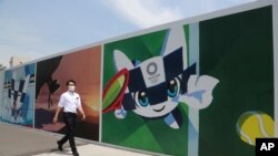 A man walks by posters promoting the Olympic Games planned to start in the summer of 2021, in Tokyo, Monday, May 24, 2021. (AP Photo/Koji Sasahara)