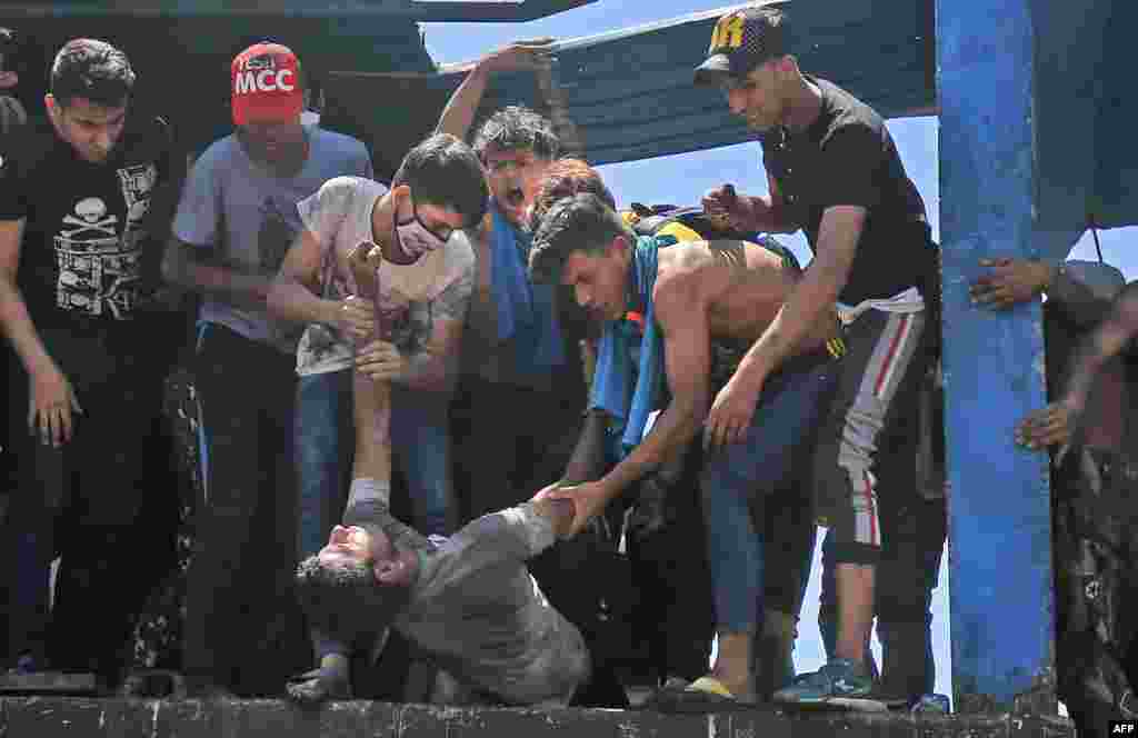 Protesters carry an injured man during clashes with security forces on Al-Jumhuriyah bridge in the capital Baghdad, Iraq, following an anti-government demonstration.