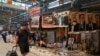 FILE - A man walks past a sign warning against the sale of illegal publications, underneath which secondhand books, images and statues of Chinese leaders are displayed for sale at the Panjiayuan antique market in Beijing, Aug. 3, 2024. 