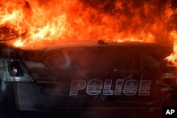 FILE - An Atlanta Police Department vehicle burns during a demonstration against police violence, May 29, 2020 in Atlanta.