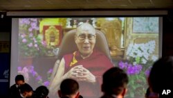 Pejabat pemerintah Tibet di pengasingan menonton penayangan pesan dari pemimpin spiritual mereka Dalai Lama (di layar) dalam upacara untuk menandai ulang tahun ke-86 pemimpin Tibet di Dharmsala, India, Selasa, 6 Juli 2021. (AP Photo/Ashwini Bhatia)