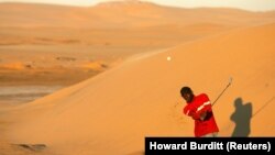 Partie de golf sur une piste unique dans le désert à Walvis Bay, en Namibie, le 16 mai 2006. REUTERS/Howard Burditt